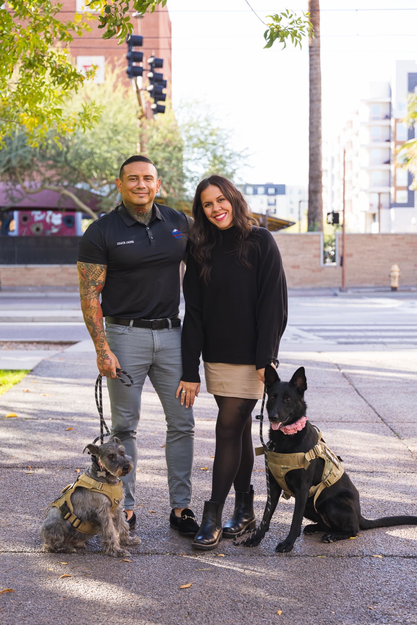 Sydney and Jaime Martinez standing with their two dogs in tactical harnesses